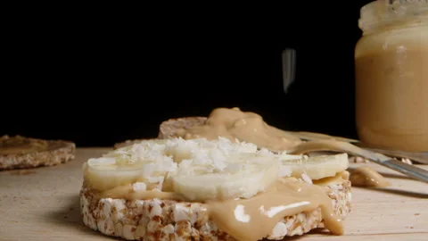 Puffed rice bread Sandwich with Peanut Butter and Banana, Sprinkled with Coconut Stock Footage 259997798