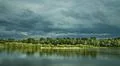 The puffy clouds above forest and river (lake) Photo