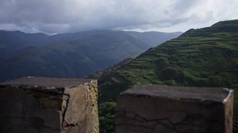 Puffy clouds drifting over lush mountainous terrain, rolling across verdant Stock Footage 297615613