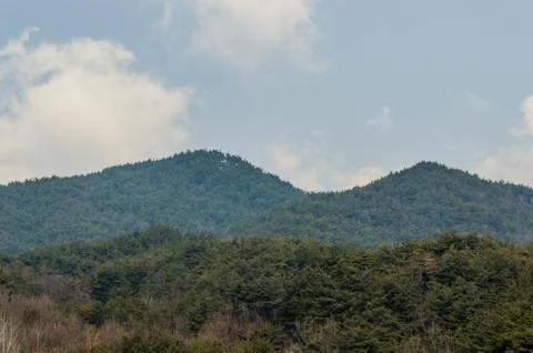 Puffy clouds over top of a mountain Stock Photos