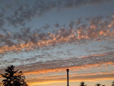 Puffy rounded clouds scatter across the sky glowing in shades of orange Stock Photos
