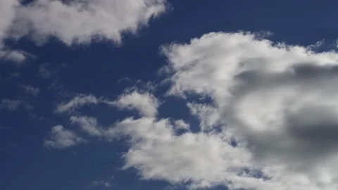 Puffy white clouds drift across bright blue sunny sky Stock Footage 329751929