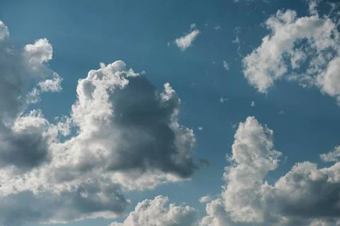 Puffy white clouds framed by intense blue sky and subtle sun rays. Foto stock