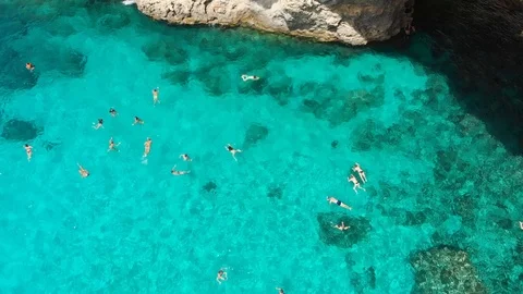 Pull Up Aerial Drone crowd of people swimming crystal clear water rocky cliffs Stock Footage 111267748