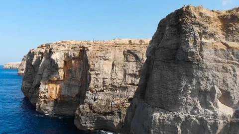 Pull Up Aerial Drone Shot waves hitting rock cliffs revealing two persons on top Stock Footage 111267140