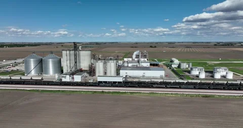 Pull ascending viewing an ethanol plant train cars siding farm fields all around Stockbeeldmateriaal 335670011
