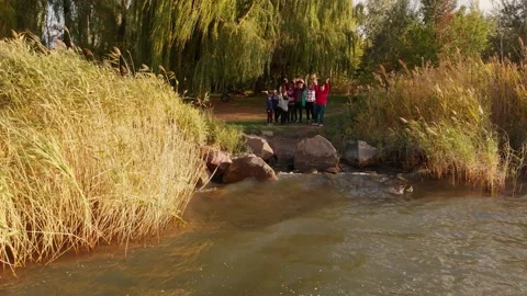 Pull away aerial shot of big friendly family rest near lake and wave hands Stock Footage 154911381