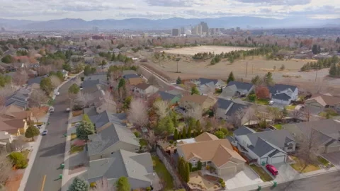 Pull away from city of Reno and mountain range and over suburban houses Stock Footage 168686437
