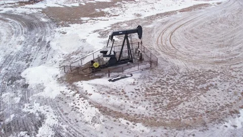 Pull away drone shot of oil pump jack near Canadian Rockies in a field Stock Footage 233616531