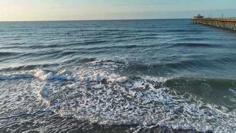 Pull back 4k drone footage of ocean waves near the a pier Stock Footage 280400793