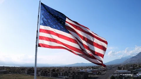 Pull back from American flag flying over busy city in USA slow motion Stock-Footage 128782659