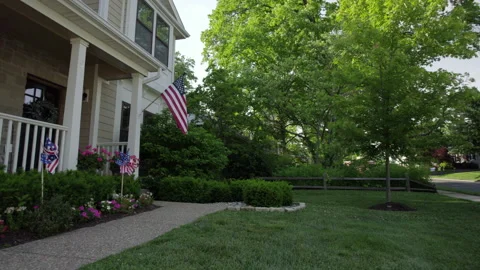 Pull back from American flag on front porch of nice house with patriotic Stock Footage 198008494