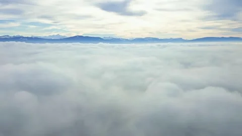 Pull back and down drone shot of sea of fog above the clouds with mountain Video stock 300938554