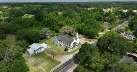 Pull back ascending flight viewing a white church in a small town Stock Footage 335672767