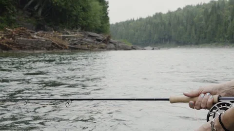 Pull back close up shot of fly fishing gear, the rod and hands as using Stock Footage 99852455
