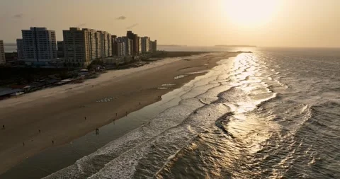 Pull back drone shot of a beach during sunset with waves lapping the shore in Stock Footage 309601936
