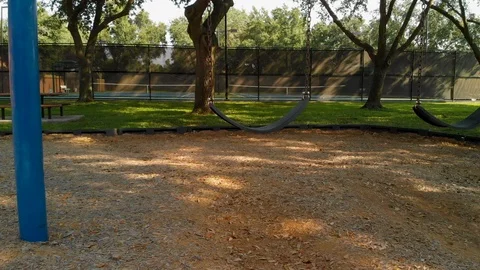 Pull back from empty swings of a playground Stock Footage 115954653