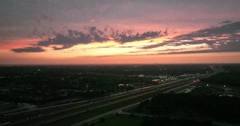 Pull back flight viewing a colorful sky and traffic moving on the pavement Stock Footage 335669903