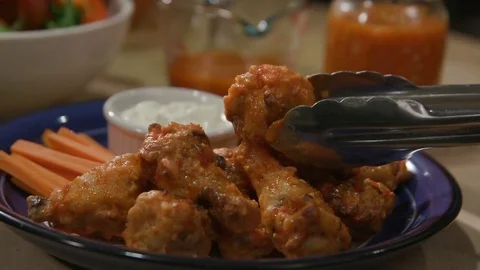 Pull Back from Hot Sauce to Chicken Wing Placed on Pile Stock Footage 81276884