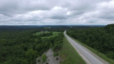 Pull back over highway with forest surrounding Stock Footage 78247540