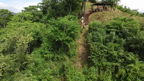 Pull back panning shot following person riding zip line across lush green Video stock 119331361
