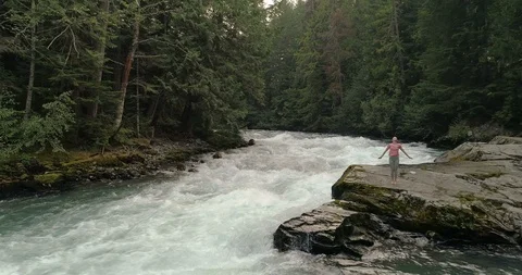 Pull Back Reveal Of Woman Doing Yoga Near A River In The Rainforest Video stock 101087712
