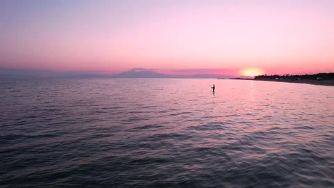 Pull back shot of man fishing during pink sunset. Video stock 161084083