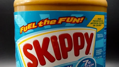 Pull back zoom out shot of a closed jar of a Skippy peanut butter, under Video stock 111599273