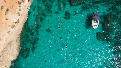 Pull down Aerial Drone crowd of people swimming crystal clear water rocky cliffs Stock Footage 111266764