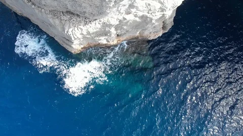 Pull down Aerial Drone Shot of waves hitting rock cliffs crystal clear blue sea Stock Footage 111267493