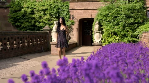 Pull Focus Between Woman Walking Through Garden and Flowers Stock Footage 44098104