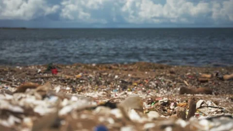 Pull focus close up of plastic waste on the dirty beach. Environmental pollution Stock Footage 245984704