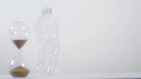Pull Focus From Crushed Plastic Bottle To Half Full Sand Timer Stock Footage 147687917