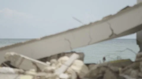 Pull focus to the rubble of a building in front of the sea Stock Footage 340820688