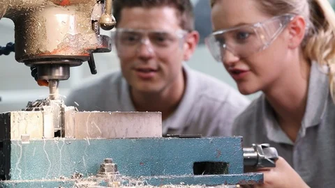 Pull Focus Shot Of Engineer Training Female Apprentice To Use Drill In Factory Stock-Footage 93376940