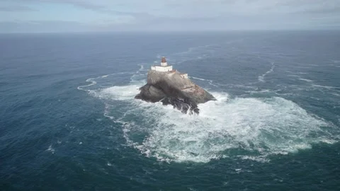 Pull out drone shot of Tillamook Rock Light lighthouse with waves crashing Stock Footage 303142788
