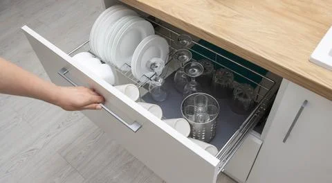 Pull-out shelf with dishes in a modular kitchen. Modern kitchen furniture Foto stock