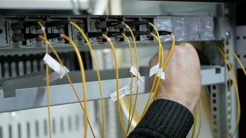 Pull-out shot of a optical fiber switchboard hub with a blurred technician Stock Footage 126949967