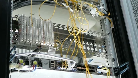 Pull-out shot of a optical fiber switchboard hub with a blurred technician Stock Footage 126954182