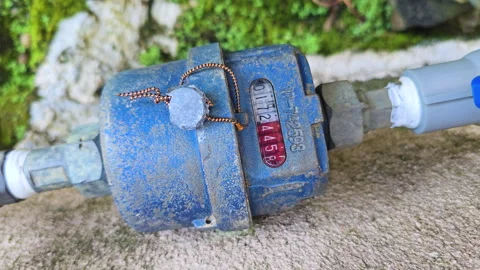 Pull-out shot of a running water meter in a moss-covered abandoned place. 4K Stock Footage 324201931