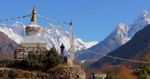 Pull out view of Namche Bazaar Nepal showing trekker by Buddhist stupa with Stockbeeldmateriaal 337395681