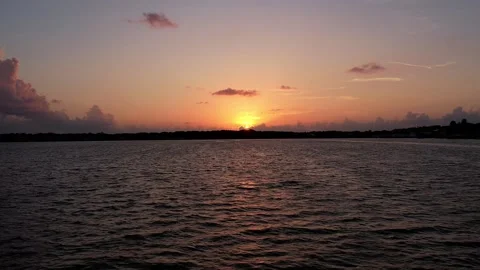 Pull shot over Florida lake with sunset in the background, surrounded by clouds. Video stock 318952619