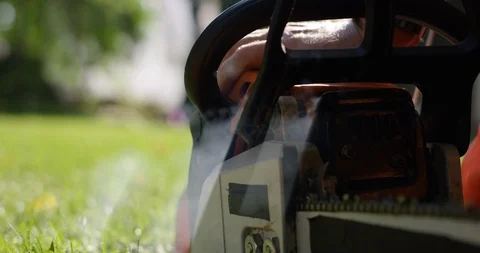 Pull starting chainsaw as smoke comes out of 2 stroke gas engine - close up Stock Footage 120668608