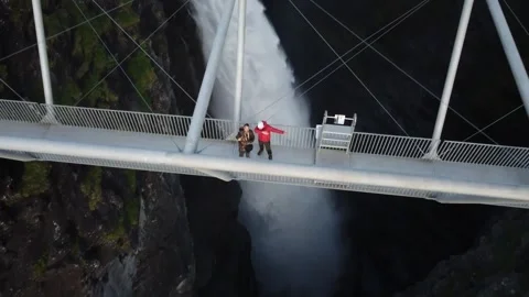 Pullback Aerial Over Two Tourists on Gorsabrua Bridge Above Gorzifossen Stock Footage 345185221