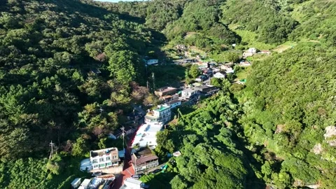 Pullback drone view of a quiet mountain village surrounded by forested hills Stock Footage 313171654