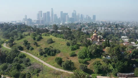 Pullback establish shot of Los Angeles downtown with lush green trees of Elysian Stock Footage 273838944