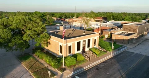 Pullback flight viewing a US post office and flag in a small downtown area Stock-Footage 335671578