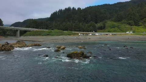 Pullback to the ocean on a rocky beach near a highway Stock Footage 152664259