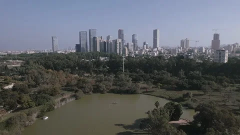 Pullback reveal of Yarkon Park lake with pedal boats and office towers in Vídeo Stock 225610271