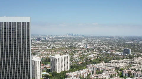 Pullback shot of Los Angeles downtown skyline through Century City buildings Stock Footage 274005349